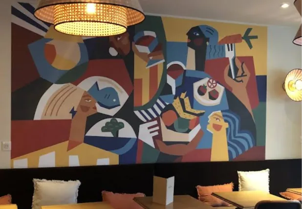 Salle intérieure du restaurant Les Maisonnaises à Maisons-Alfort, avec fresque murale colorée